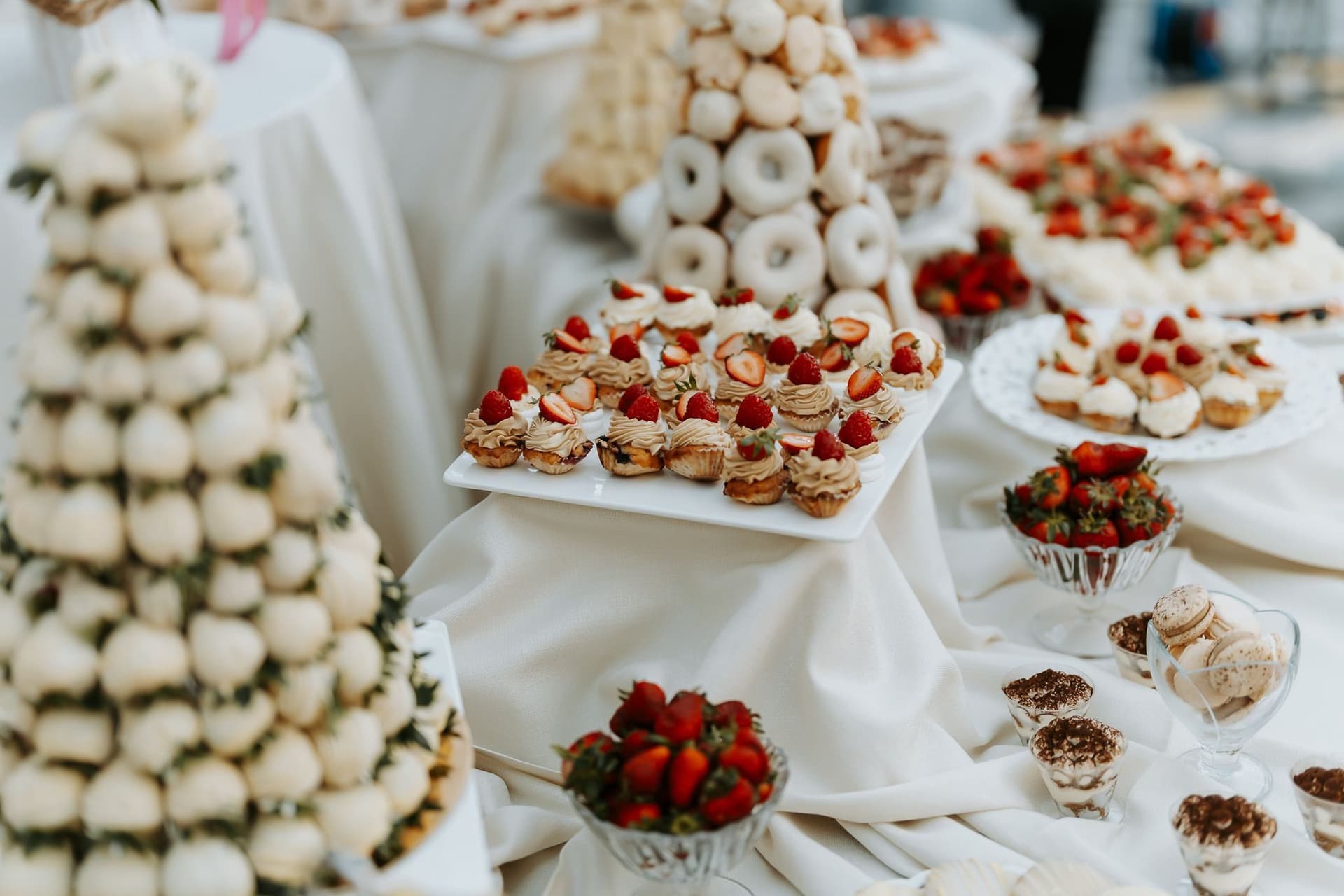 Candy Bar cu prăjituri mici și un tort de profiterol, pe mese albe