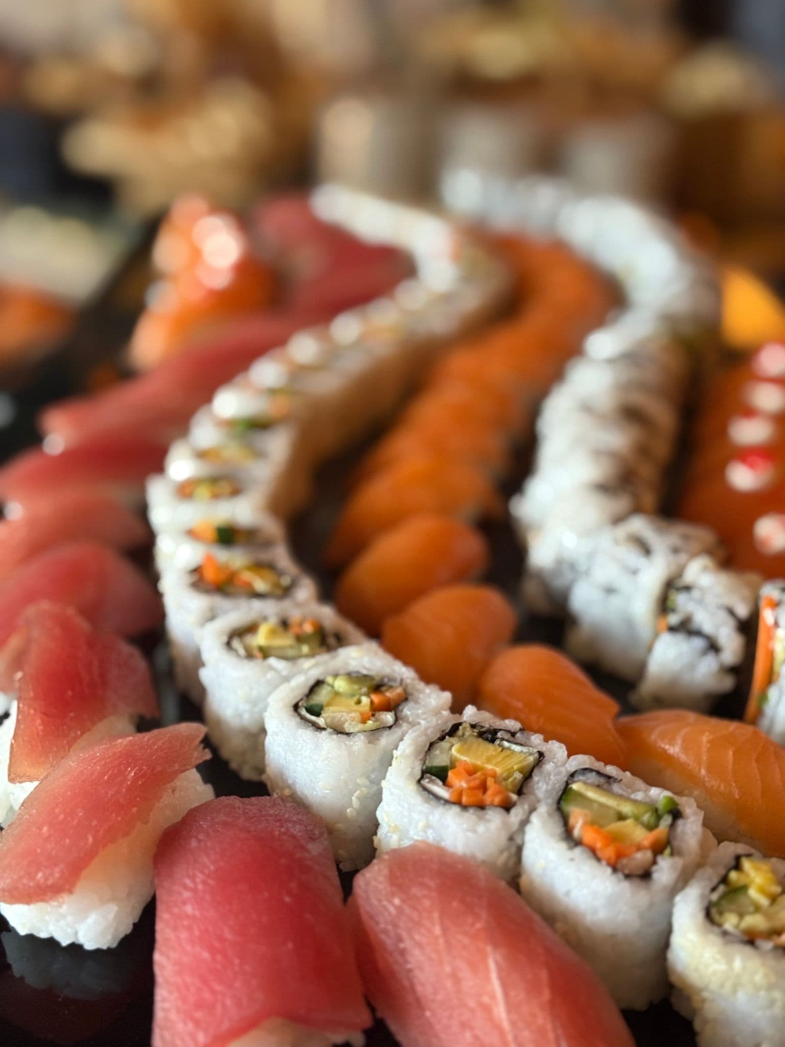 Rulouri de sushi cu somon, așezate pe platou
